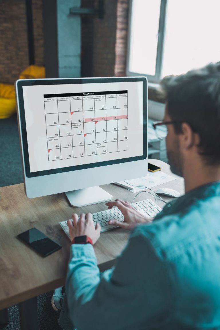 Kalender på skærm mens medarbejder sidder foran PC