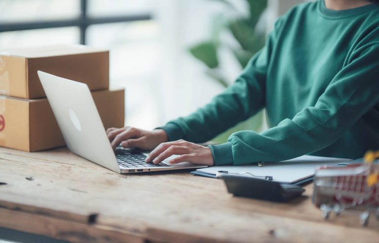 Person sidder ved laptop i webshop omgivelser
